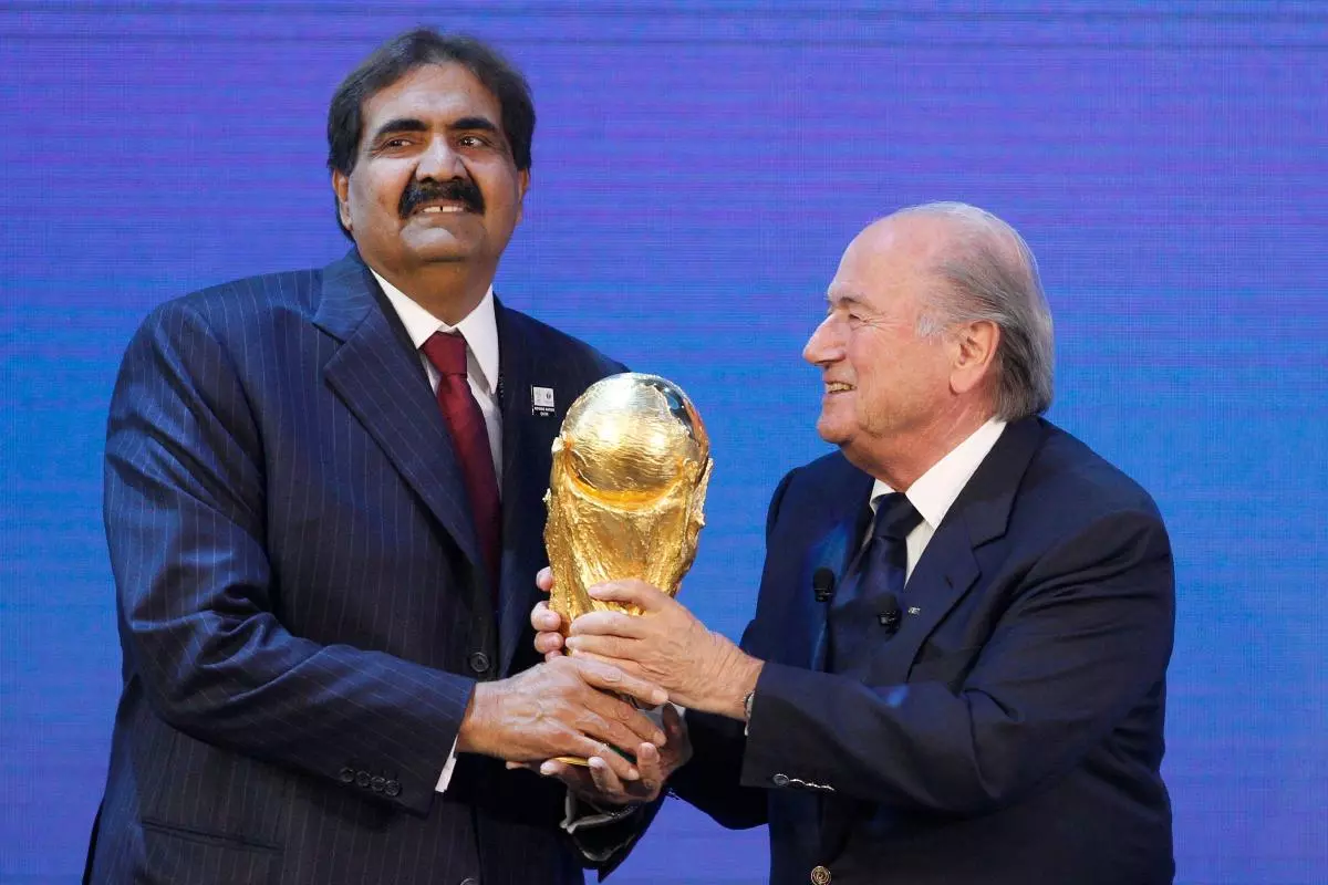 FIFA president Sepp Blatter hands over a copy of the World Cup to Qatar's Emir Sheikh Hamad bin Khalifa al Thani 