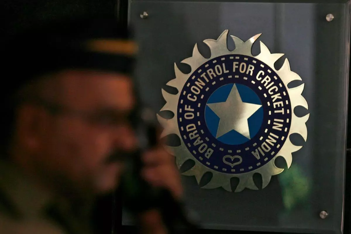 A policeman walks past a logo of the Board of Control for Cricket in India (BCCI)