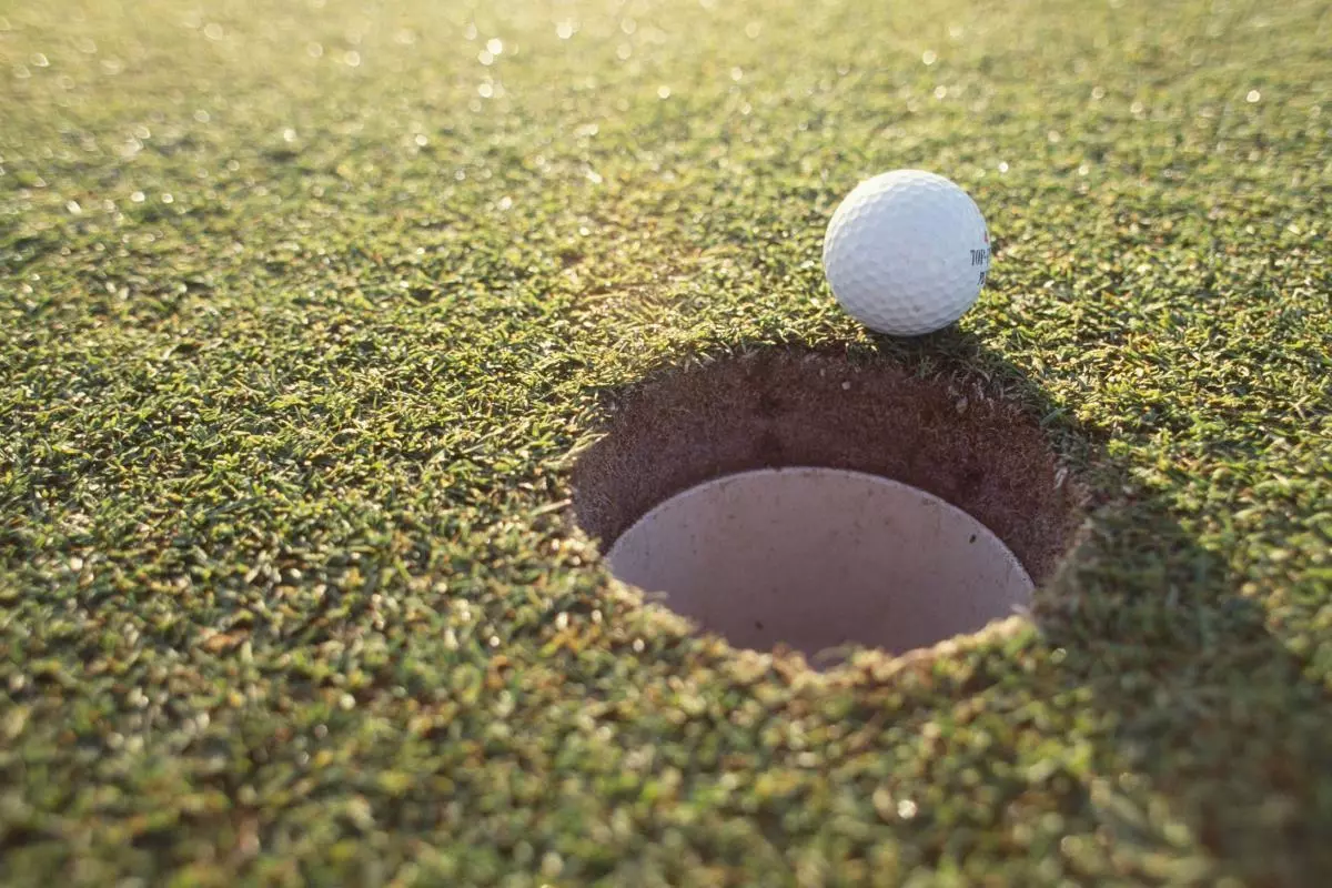 Golf ball sitting on the edge of the cup, missed shot