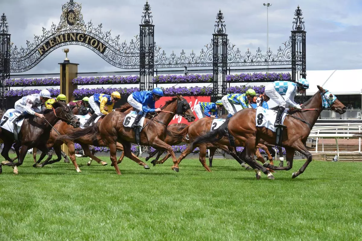 Jockeys and people take part during Melbourne Cup Carnival 2022 at Flemington Racing Club Victoria Derby Day in Melbourne