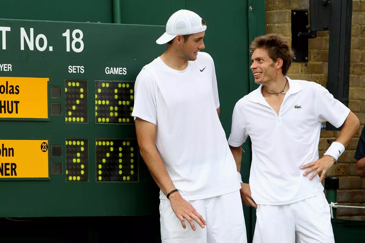 USA's John Isner celebrates victory over France's Nicolas Mahut (right) as they stand by the score board, in their record breaking match on Court 18 during Day Four of the 2010 Wimbledon Cham