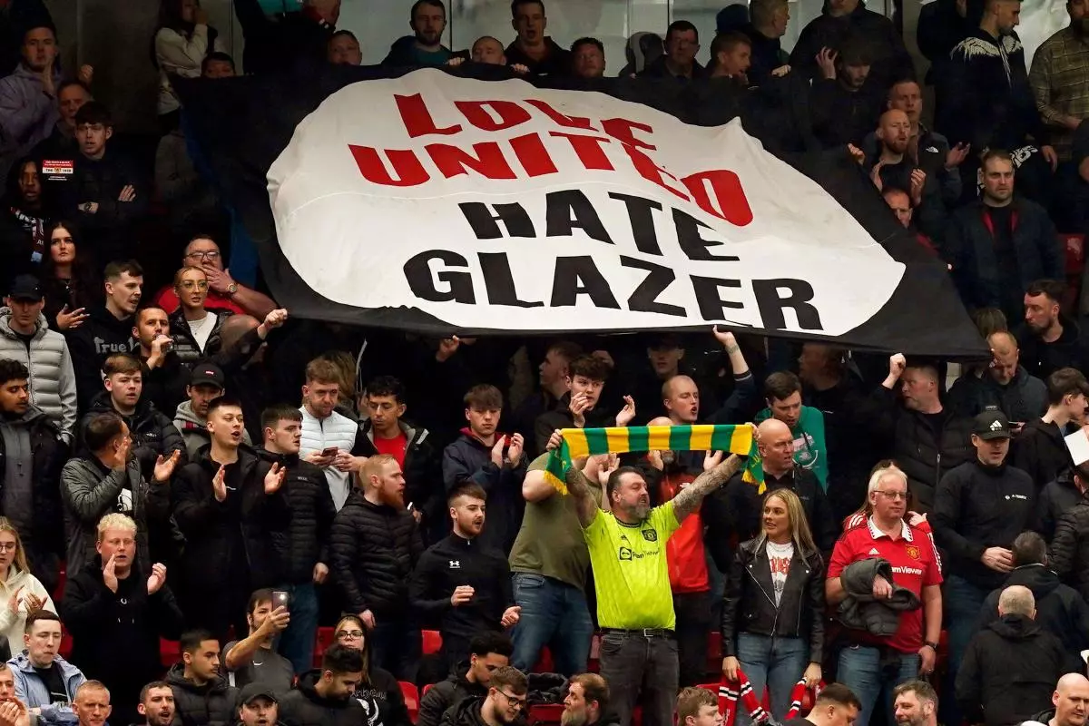 Manchester United fans hold up a Glazers Out banner at old Trafford