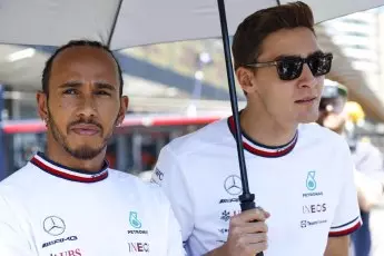 Lewis Hamilton and George Russell under an umbrella.
