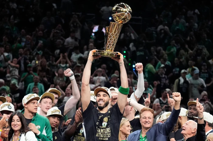 Boston Celtics forward Jayson Tatum holds, center, up the Larry O'Brien Championship Trophy at NBA Finals