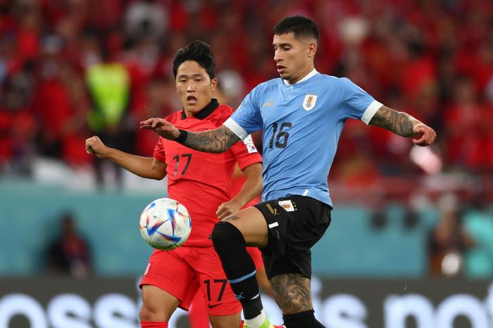 Mathias Olivera of Uruguay collects the ball ahead of Sangho Na of Korea